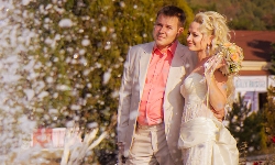 свадебный фотограф снимает свадебную прогулку жениха и невесты у фонтана в Абрау