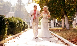 свадебный фотограф снимает свадебную прогулку жениха и невесты у винзавода в Абрау